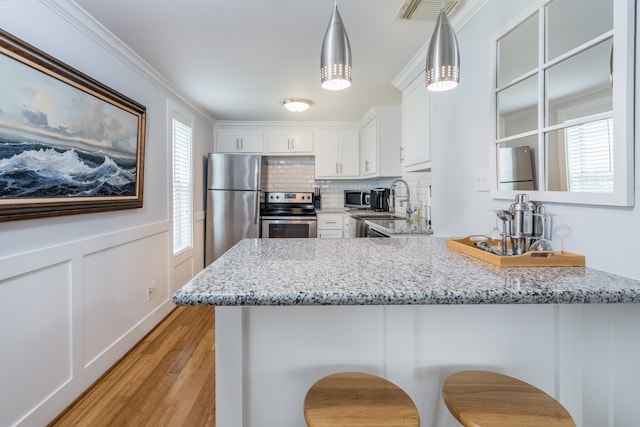 kitchen with white cabinetry, a wealth of natural light, a kitchen bar, and stainless steel appliances