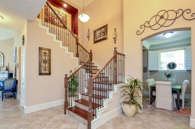 stairs featuring ornamental molding and a high ceiling