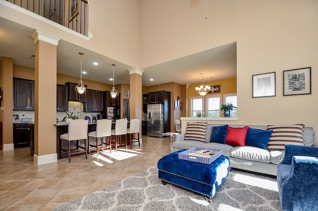 living room featuring a high ceiling, ornate columns, and an inviting chandelier