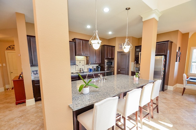 kitchen featuring stainless steel appliances, tasteful backsplash, light stone countertops, a breakfast bar area, and decorative light fixtures