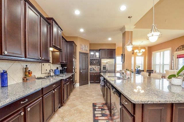 kitchen featuring stainless steel appliances, sink, an island with sink, backsplash, and pendant lighting