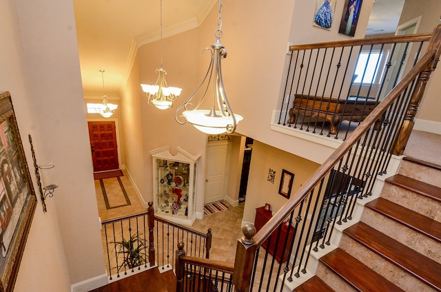 staircase with a chandelier and crown molding