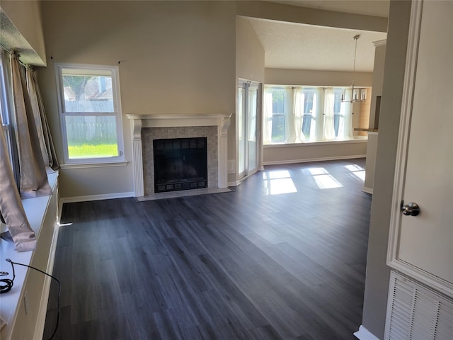 unfurnished living room featuring dark wood-type flooring, plenty of natural light, and a tile fireplace