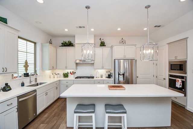 kitchen with a center island, hanging light fixtures, sink, dark hardwood / wood-style floors, and appliances with stainless steel finishes