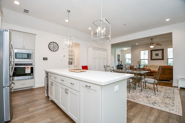 kitchen featuring pendant lighting, light wood-type flooring, appliances with stainless steel finishes, and a center island