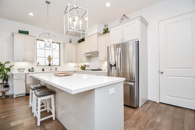 kitchen featuring white cabinets, a center island, and stainless steel fridge