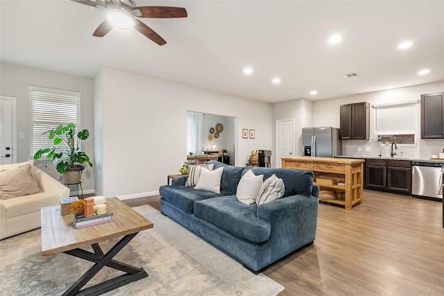 living room with sink, ceiling fan, and light wood-type flooring