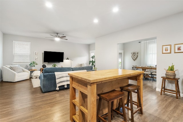 kitchen featuring hardwood / wood-style flooring, butcher block countertops, a breakfast bar, and ceiling fan