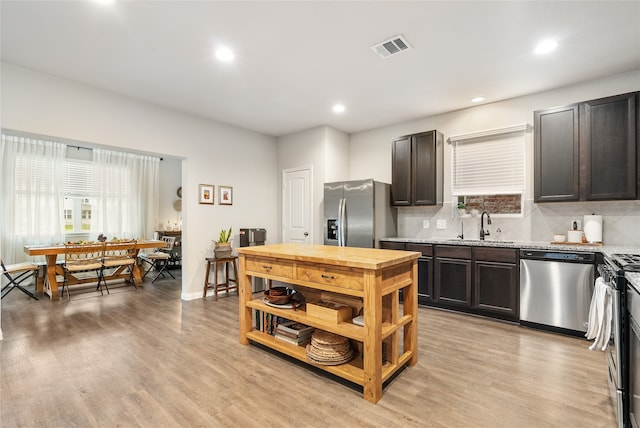 kitchen featuring stainless steel appliances, light stone countertops, dark brown cabinets, and light hardwood / wood-style floors