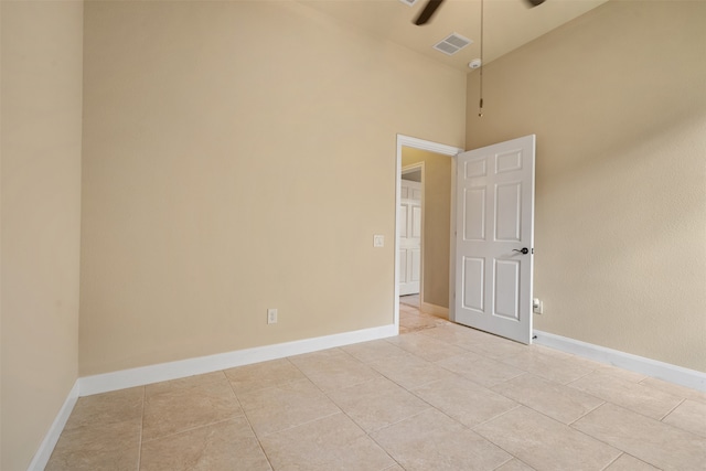 unfurnished room with a towering ceiling and light tile patterned floors