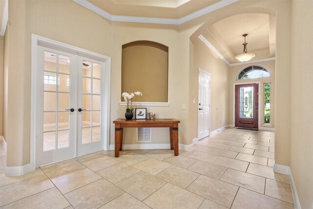 tiled foyer entrance with french doors, a raised ceiling, and crown molding