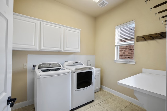 laundry area featuring cabinets, light tile patterned floors, and washer and clothes dryer