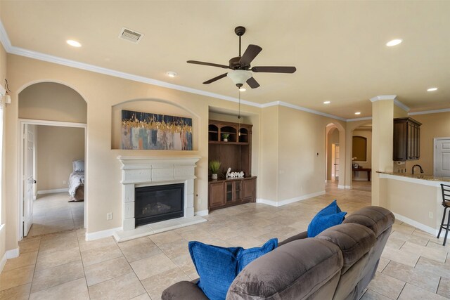 tiled living room featuring ceiling fan, crown molding, and sink