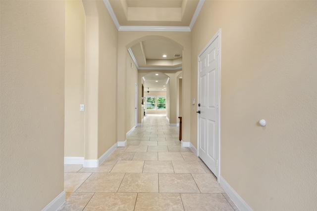 hall with a tray ceiling, light tile patterned floors, and crown molding