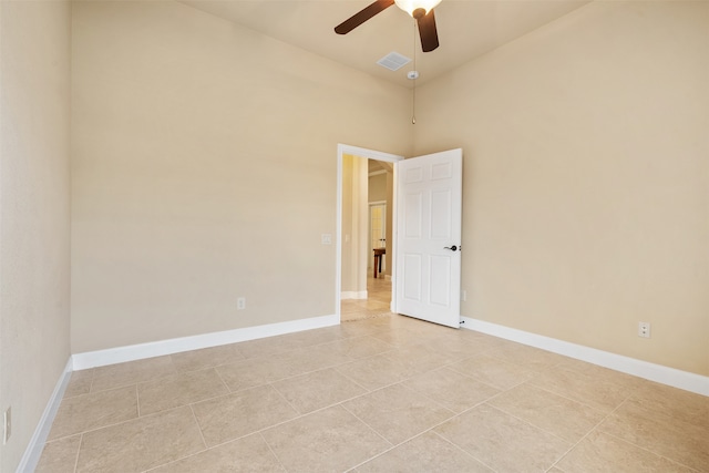 tiled spare room featuring a towering ceiling and ceiling fan