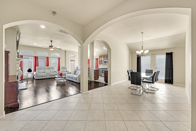 living room with ceiling fan with notable chandelier, a healthy amount of sunlight, and light wood-type flooring