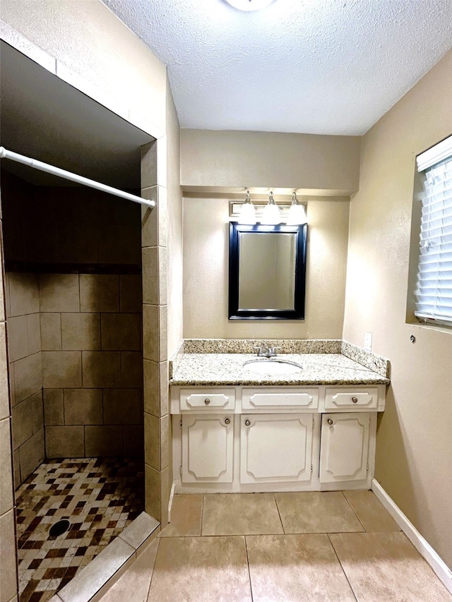 bathroom featuring vanity, a textured ceiling, tile patterned flooring, and tiled shower