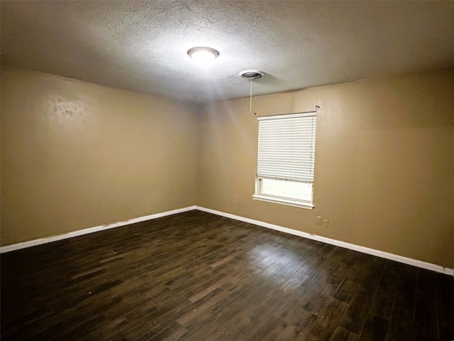 unfurnished room featuring dark wood-type flooring and a textured ceiling