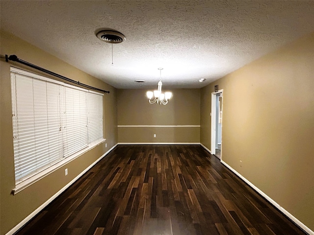 unfurnished dining area with dark hardwood / wood-style floors, a textured ceiling, and a chandelier