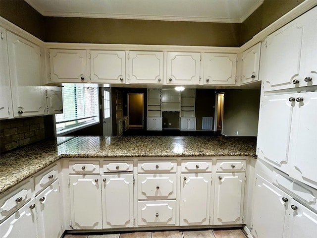 kitchen featuring white cabinets, dark stone counters, and crown molding