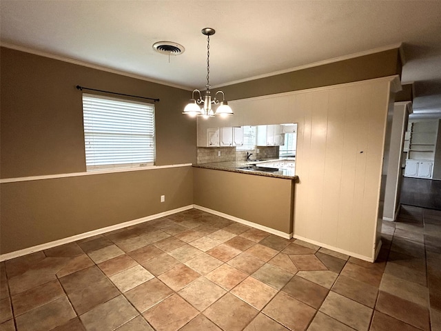 unfurnished dining area featuring an inviting chandelier and crown molding