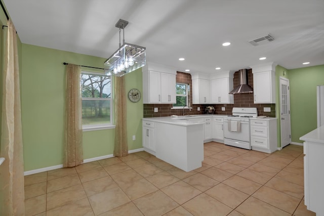 kitchen featuring backsplash, white stove, wall chimney range hood, sink, and white cabinetry