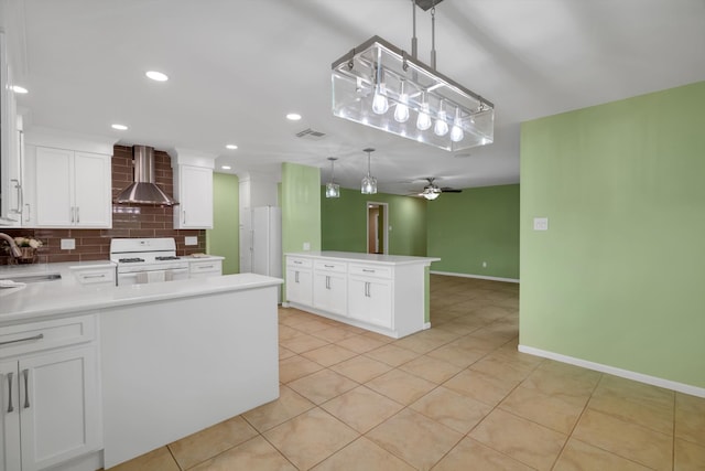 kitchen featuring kitchen peninsula, wall chimney exhaust hood, white range, pendant lighting, and white cabinets