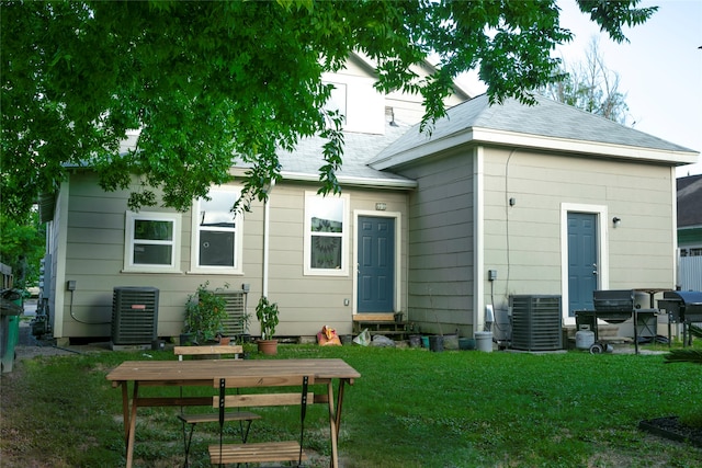 rear view of property featuring a yard and central AC unit