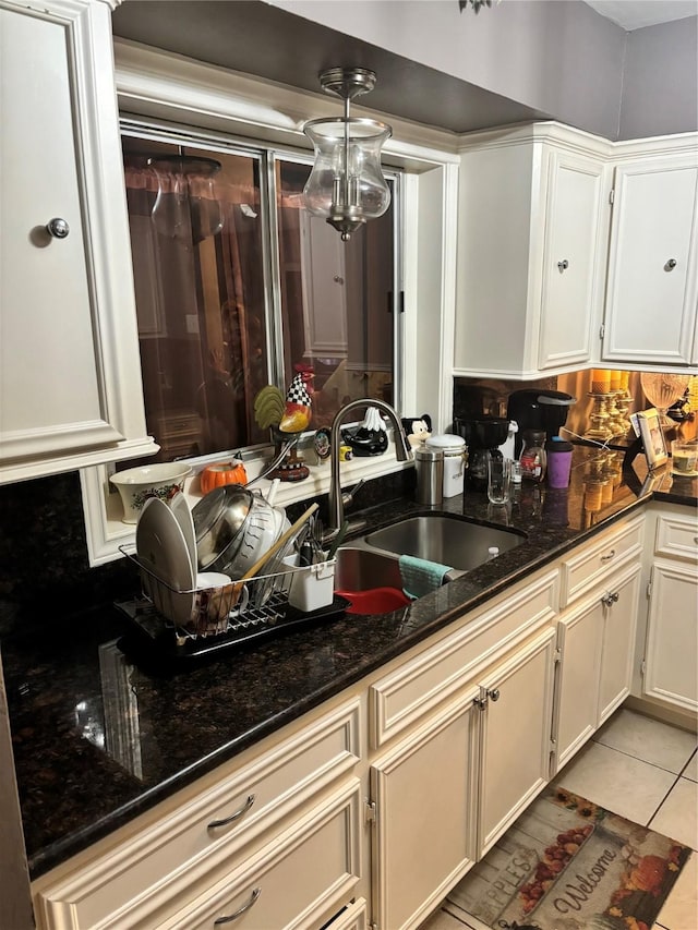 kitchen featuring light tile patterned floors, white cabinetry, dark stone counters, and sink