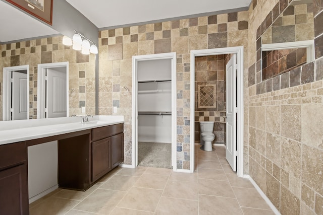 bathroom featuring toilet, vanity, tile walls, and tile patterned flooring