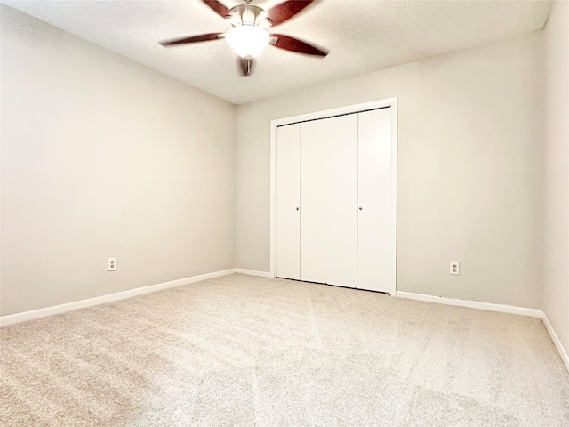 unfurnished bedroom featuring carpet, a textured ceiling, a closet, and ceiling fan