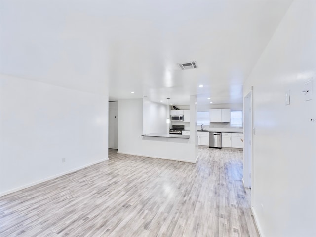 unfurnished living room featuring sink and light hardwood / wood-style flooring