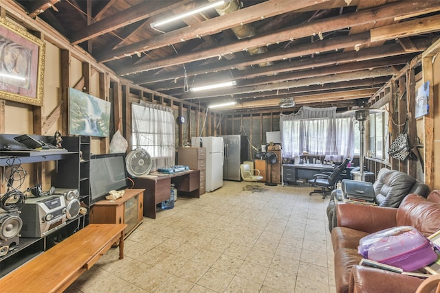 basement featuring white refrigerator and stainless steel fridge