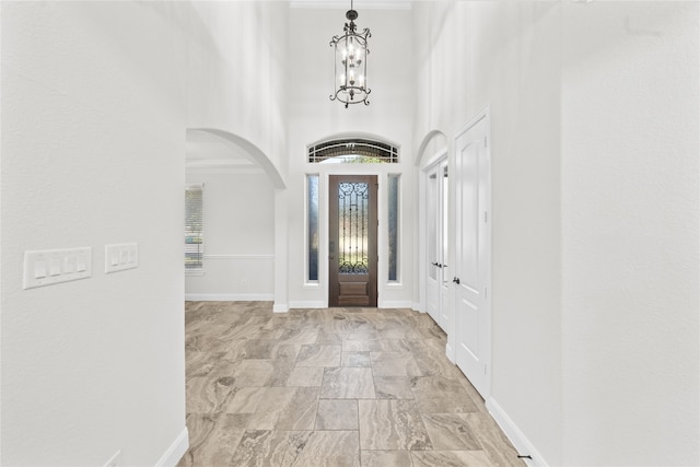 foyer entrance with a towering ceiling, an inviting chandelier, and ornamental molding