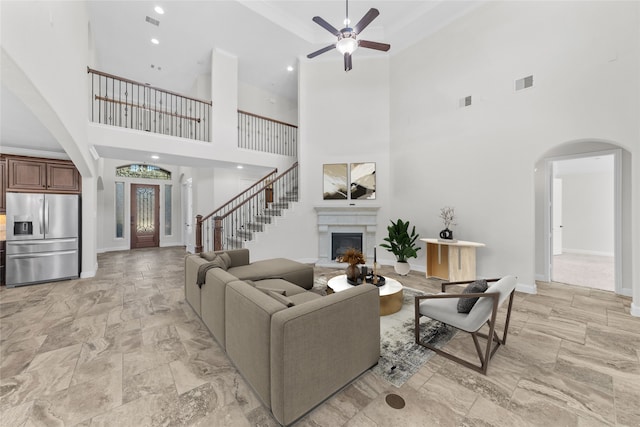 living room with ceiling fan and a towering ceiling