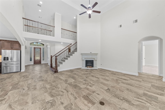 unfurnished living room with ceiling fan and a towering ceiling