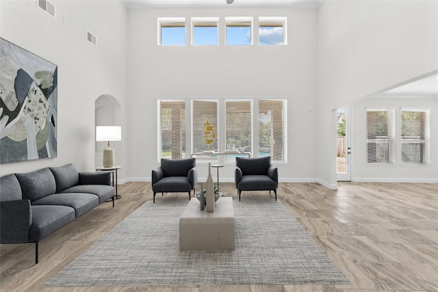 living room with a towering ceiling, plenty of natural light, and crown molding