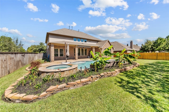 rear view of house featuring a yard, an in ground hot tub, and a patio