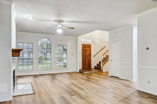 unfurnished living room featuring light hardwood / wood-style floors, a textured ceiling, crown molding, and ceiling fan