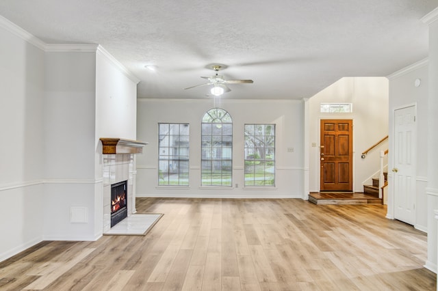 unfurnished living room featuring ceiling fan, a textured ceiling, light wood-type flooring, and ornamental molding