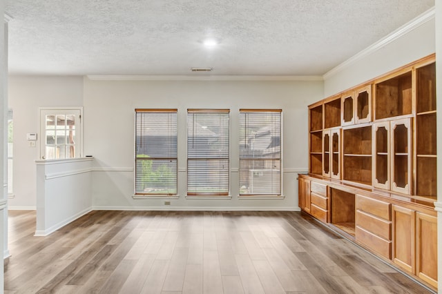 interior space featuring a textured ceiling, ornamental molding, and light hardwood / wood-style flooring