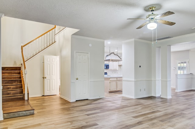 unfurnished living room featuring ornamental molding, light wood-type flooring, a textured ceiling, and ceiling fan