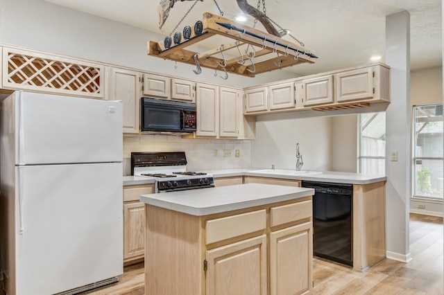 kitchen with light wood-type flooring, sink, black appliances, and a kitchen island