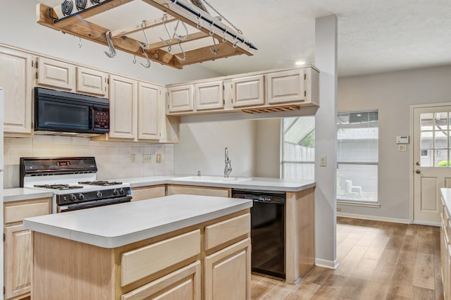 kitchen with light hardwood / wood-style floors, sink, black appliances, a textured ceiling, and a kitchen island