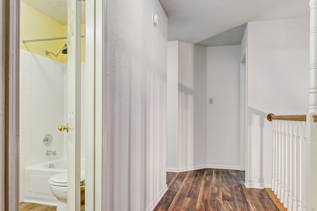 hall with a textured ceiling and dark hardwood / wood-style flooring