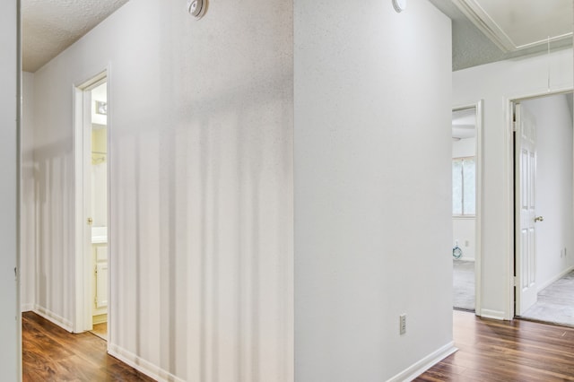 corridor with dark hardwood / wood-style flooring and a textured ceiling