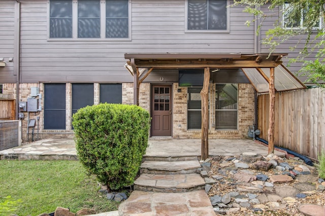 view of exterior entry with central AC unit and a patio area