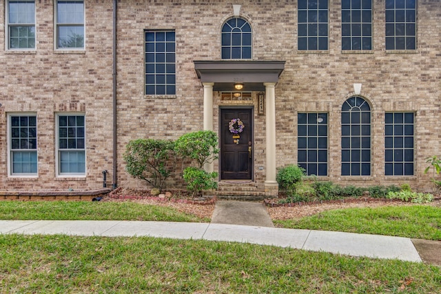 view of exterior entry featuring a lawn