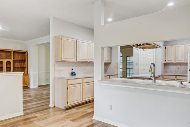 kitchen with crown molding, sink, light wood-type flooring, and decorative backsplash