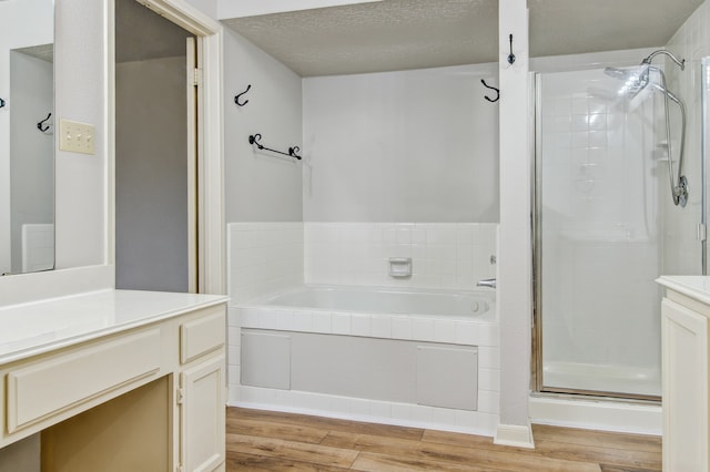 bathroom with vanity, shower with separate bathtub, hardwood / wood-style floors, and a textured ceiling